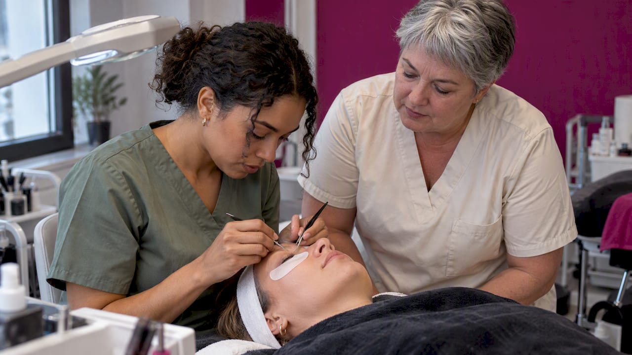 Teilnehmerin trainiert Wimperntechnik an einem Modell